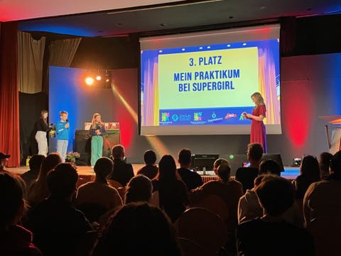 Zwei Teammitglieder von "Mein Praktikum bei Supergirl" bei der Präsentation ihres Films auf der Bühne des Schulterblick Kinder & Jugendfilmfestivals in Berlin 2025.