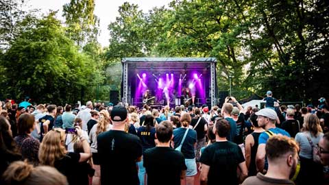 Farbiges Setfoto vom Young Sound Festival 2026 mit Zuschauern im Vordergrund und der Band "Heavy Saurus" auf der Bühne im Hintergrund.